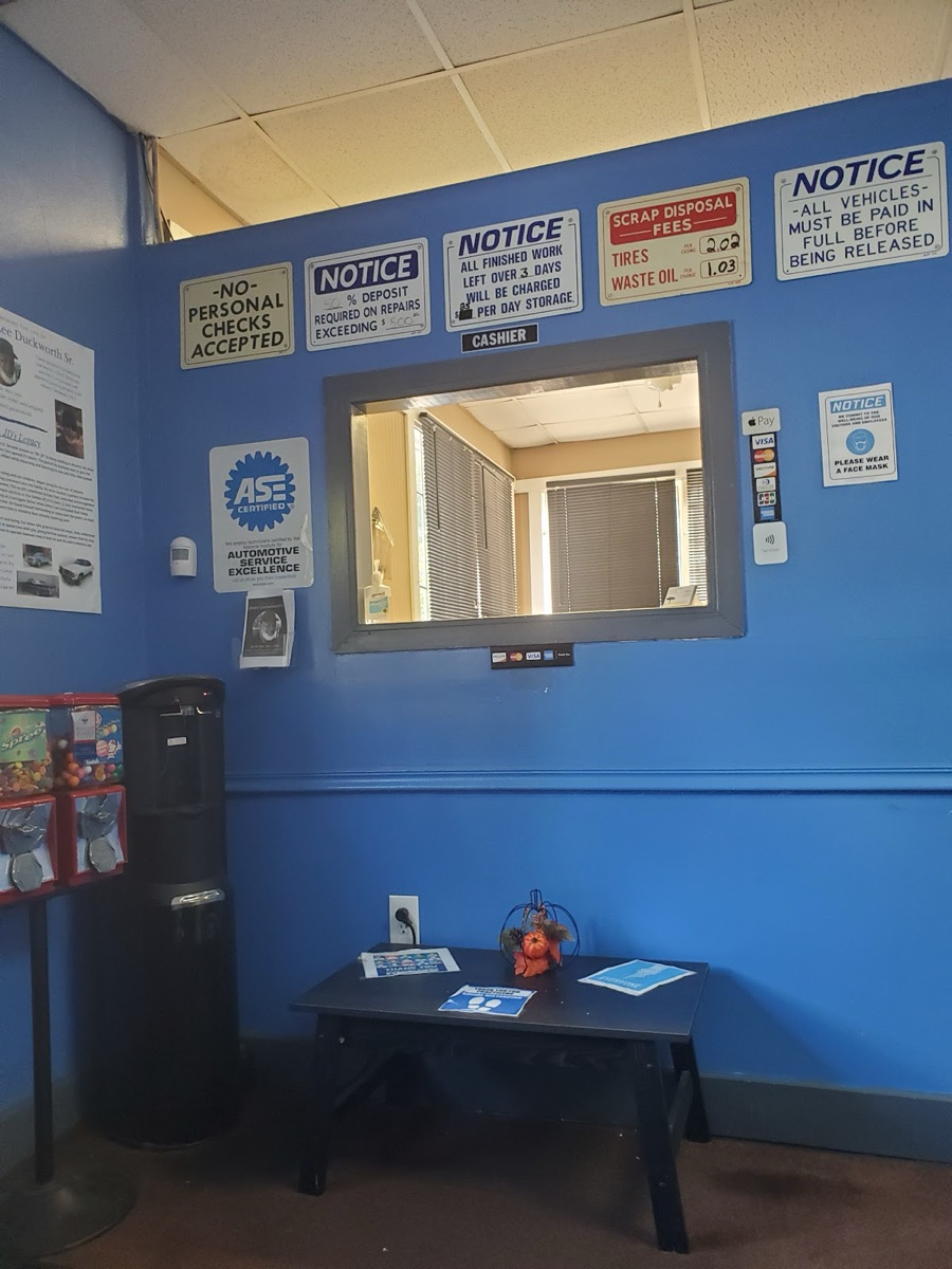 Inside J D Auto Services — ASE Certified badge, accepted-payment and shop policy notices at the cashier window